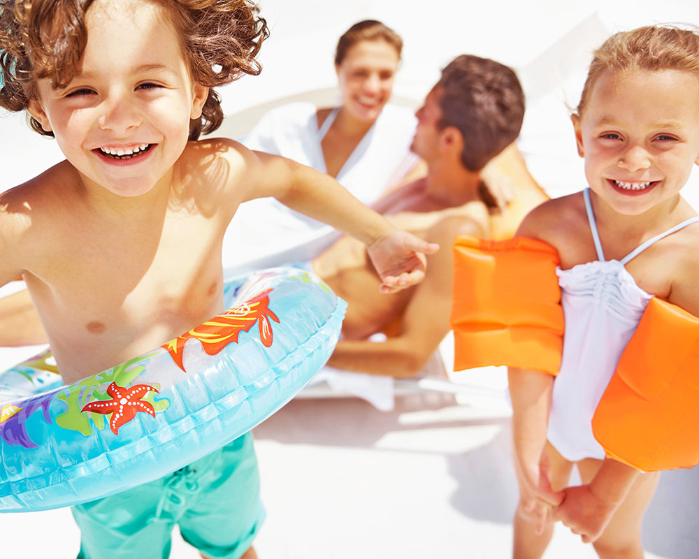 Cute siblings playing together while on a beach vacation with their family