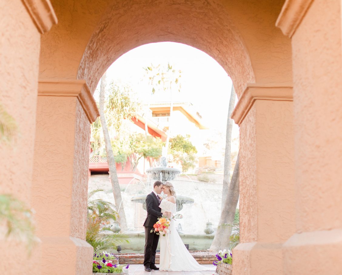 View More: http://ivonneandtravisphotography.pass.us/tapatiocliffs Bride and groom embracing on an outdoor patio next to a large water fountain