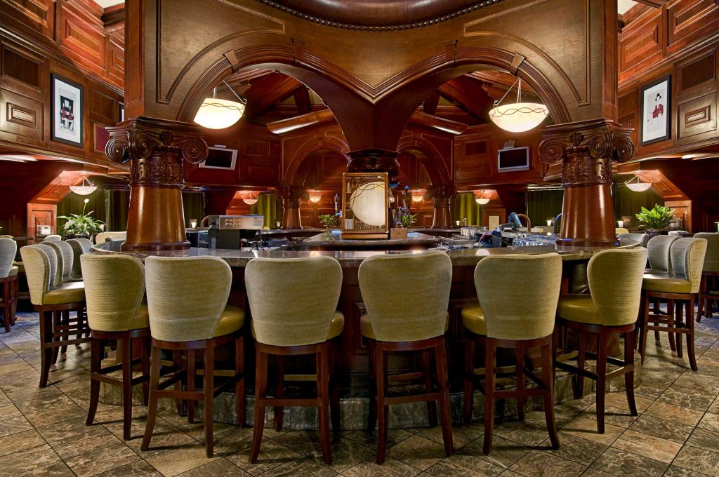 Pointe In Tyme bar seating surrounded by rich mahogany wood accents and two flat screen TVs